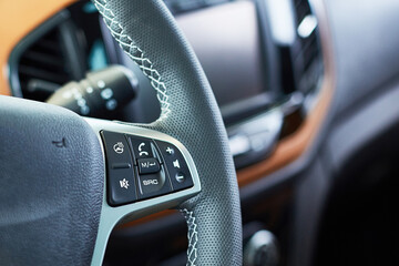 steering wheel of a new modern car with audio control buttons and calls, close up, selective focus