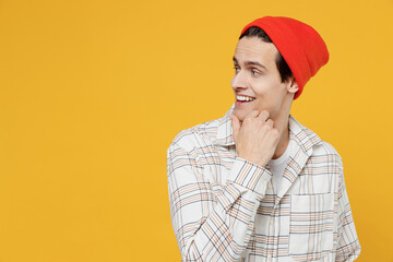 Young minded happy cool fun man 20s wearing white casual shirt orange hat look aside on workspace area prop up chin isolated on plain yellow color background studio portrait. People lifestyle concept.