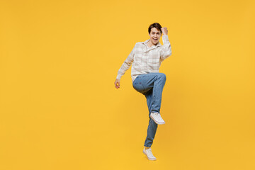 Fototapeta na wymiar Full body young fun smiling happy caucasian man 20s wearing white casual shirt doing winner gesture celebrate clenching fists say yes raise up leg isolated on plain yellow background studio portrait