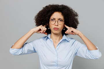 Young employee business corporate lawyer woman of African American ethnicity in classic formal shirt work in office cover ears hands fingers do not want to listen scream isolated on grey background