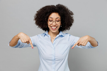 Young employee business corporate lawyer woman of African American ethnicity in classic formal shirt work in office point index finger down on wrkspace advert isolated on grey color background studio.