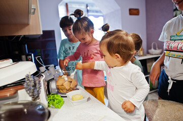 Mother with kids cooking at kitchen, happy children's moments.