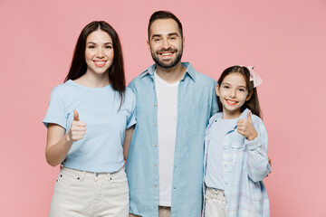 Young happy cool parents mom dad with child kid daughter teen girl in blue clothes showing thumb up like gesture isolated on plain pastel light pink background Family day parenthood childhood concept