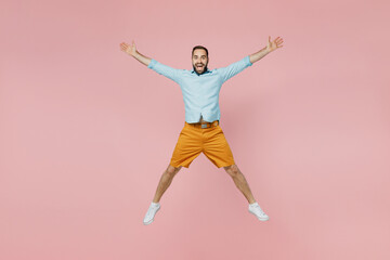 Fototapeta na wymiar Full length young excited overjoyed winner fun happy caucasian man 20s wearing classic blue shirt jump high with outstratched hands legs isolated on plain pastel light pink background studio portrait
