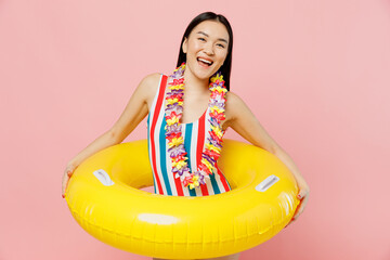 Young smiling cheerful fun woman of Asian ethnicity in striped one-piece swimsuit hawaii lei hold...