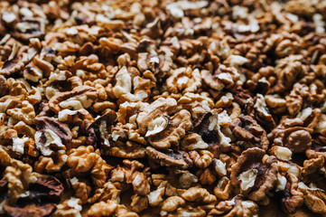 Background, texture of many brown pieces of walnuts made of wood, peeled nuts lying on a wooden table. Food photography, top view.