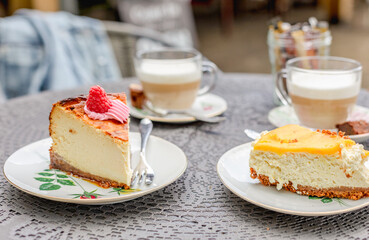 Two pieces of cake and two cups of cappuccino on a table outdoor