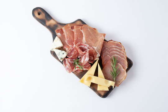Appetizers table with different antipasti, charcuterie, snacks and cheese. Buffet party. Wooden cutting board isolated on white background, top view