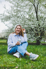 Young beautiful blonde woman in blooming almonds garden.