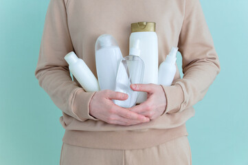 Caucasian woman holding white bottles cosmetics in her hands.