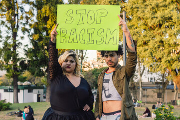 young woman and homosexual man outdoors protesting holding sign that says 