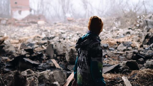 A teenager walks through the ruins of a destroyed building. Shooting in motion from the side