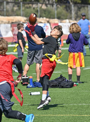 Obraz premium Young athletic boy catching, running and throwing the ball in a football game