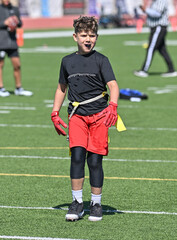Young athletic boy catching, running and throwing the ball in a football game