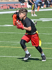 Obraz premium Young athletic boy catching, running and throwing the ball in a football game