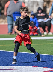Fototapeta premium Young athletic boy catching, running and throwing the ball in a football game