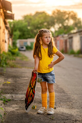 girl is standing on the road and holding a skateboard © Olena