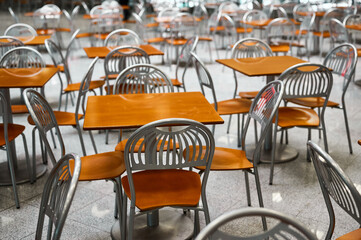 Wooden tables and chairs at large empty foodcourt in mall