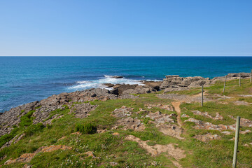 Cliffs surrounded by vegetation under a cloudless sky.
