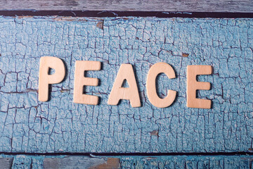 Peace letter word written on wooden text on a blue textured board