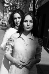 Black and white portrait of two girls. Girls in white dresses walking in the park