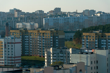 Top view of the sleeping area of a big city. Autumn city landscape. Green spaces next to high-rise modern buildings.