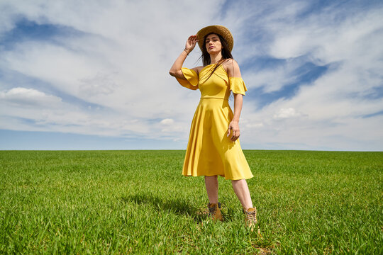 Farmer lady in yellow dress and straw hat in a field