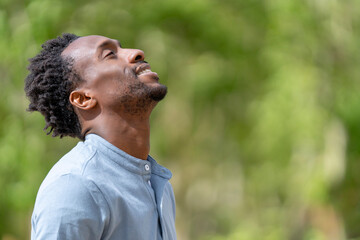Relaxed man with black skin in spring breathing fresh air outdoors - obrazy, fototapety, plakaty