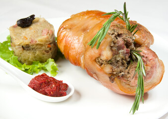 Appetizing baked pork galyonka on a white plate with spices and herbs.