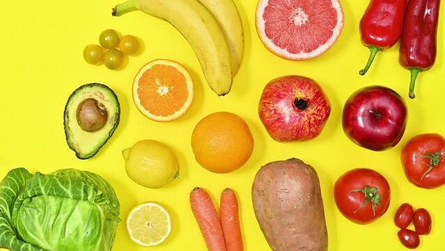 Organic healthy fruits and vegetables in vivid colors make pattern on yellow background. Stop motion flat lay