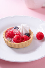 Tartlet with fresh berries and cream for pink background in hard light