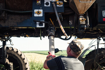The tractor sprays the sprayer with pesticides in the field. Man near a self-propelled sprayer