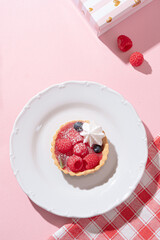 Tartlet with fresh berries and cream for pink background in hard light