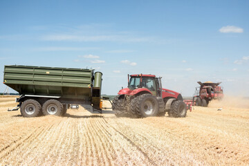 The combine unloads the harvested grain into a tractor trailer in the field.