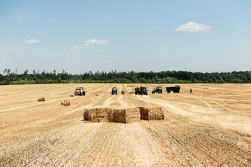 Straw bales on the field on the background of tractors