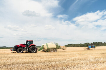 Tractor collects straw in bales on the field. special agricultural machinery. Harvesting hay, straw. Field with bales