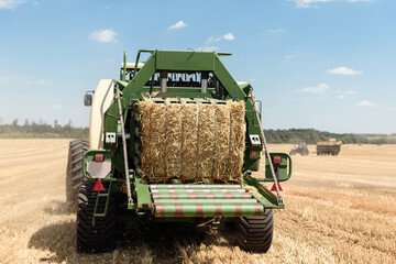 Tractor collects straw in bales on the field. special agricultural machinery. Harvesting hay, straw. Field with bales
