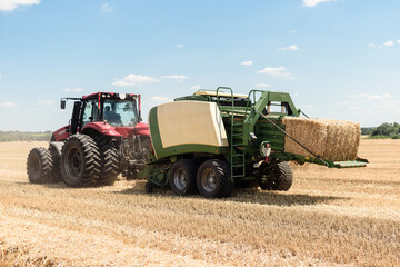 Tractor collects straw in bales on the field. special agricultural machinery. Harvesting hay, straw. Field with bales