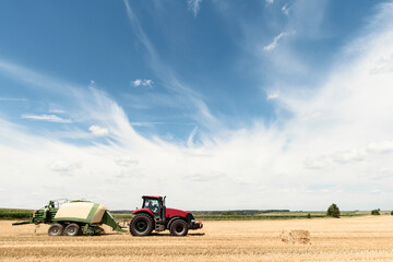 Tractor collects straw in bales on the field. special agricultural machinery. Harvesting hay, straw. Field with bales