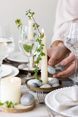 Rustic zero waste wedding decor with natural elements. Wooden table, candles, linen napkins, branches with green leaves. Eco-friendly decoration for the special dinner. Romantic and cozy place