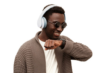Portrait of smiling african man with smartwatch using voice command recorder or takes calling in wireless headphones listening to music isolated on white background