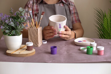 Women in gray apron hold a white flower ceramic pot