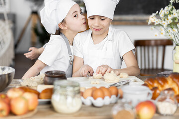 Brother and sister baking homemade sweet pie together, having fun. Home bakery, little kids in process of food preparation in the kitchen at home, helping mother, doing chores