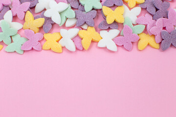 Colorful butterflies, popular sugar candy sprinkles, lie on top of a pink background.