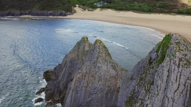 Aerial drone view flying around three cliffs at high tide. Three Cliffs Bay, Gower, Wales