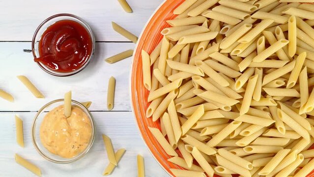 Uncooked raw italian penne pasta rotating slowly.
