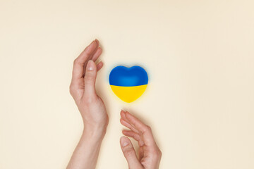 Heart with print the national flag of ukraine in female hands. Flat lay. Copy space.