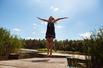 Fototapeta na wymiar Young happy woman jumping on the nature in summer