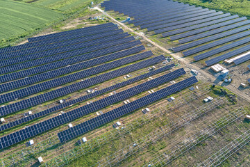 Aerial view of big electric power plant under construction with many rows of solar panels on metal frame for producing clean electrical energy. Development of renewable electricity sources