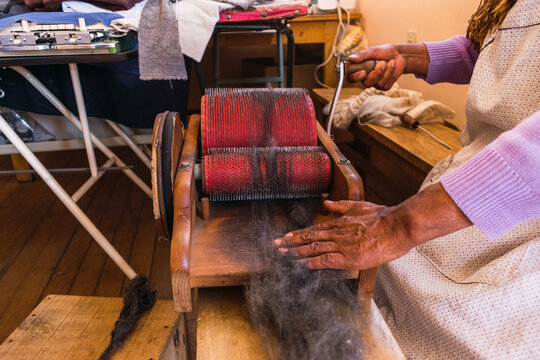 hands of an andean woman spinning black alpaca fiber in the Andes mountain range in an artisan workshop illuminated with natural light